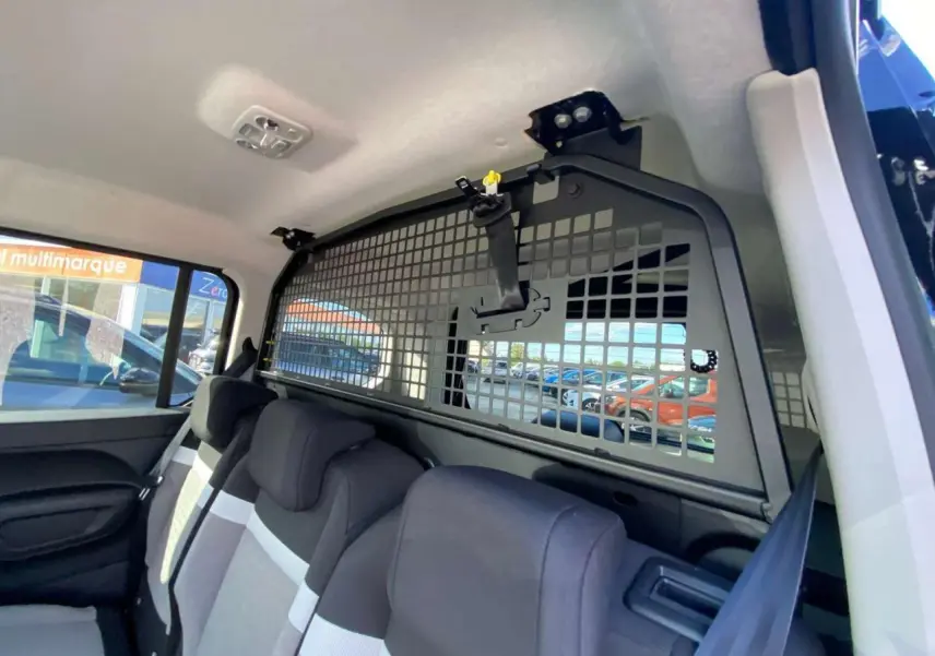 Vue intérieure arrière du Citroën Berlingo noir 2026 montrant la grille de séparation et les sièges arrière.