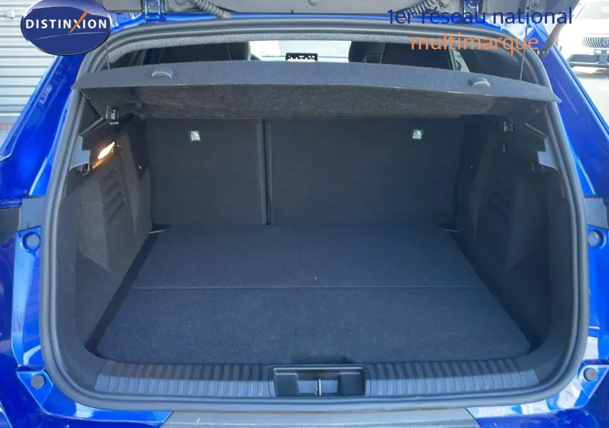 Coffre ouvert vu de l'arrière d'une Renault Symbioz bleu iron metal, montrant un espace de chargement propre et spacieux.