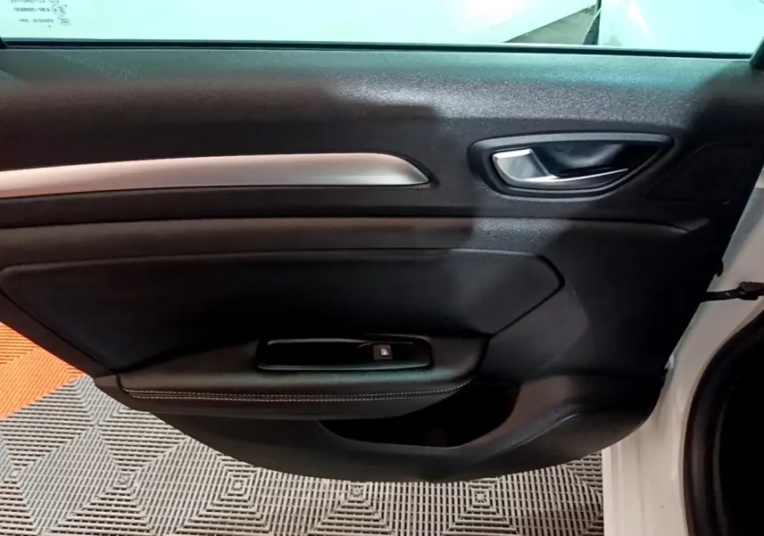 Vue rapprochée de la porte avant droite noire avec poignée argentée d’une Renault Mégane blanche 2023.
