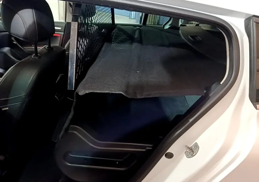 Vue intérieure côté droit du coffre de la Renault Mégane Techno TCe 140 blanc avec banquette rabattue et séparation métallique.