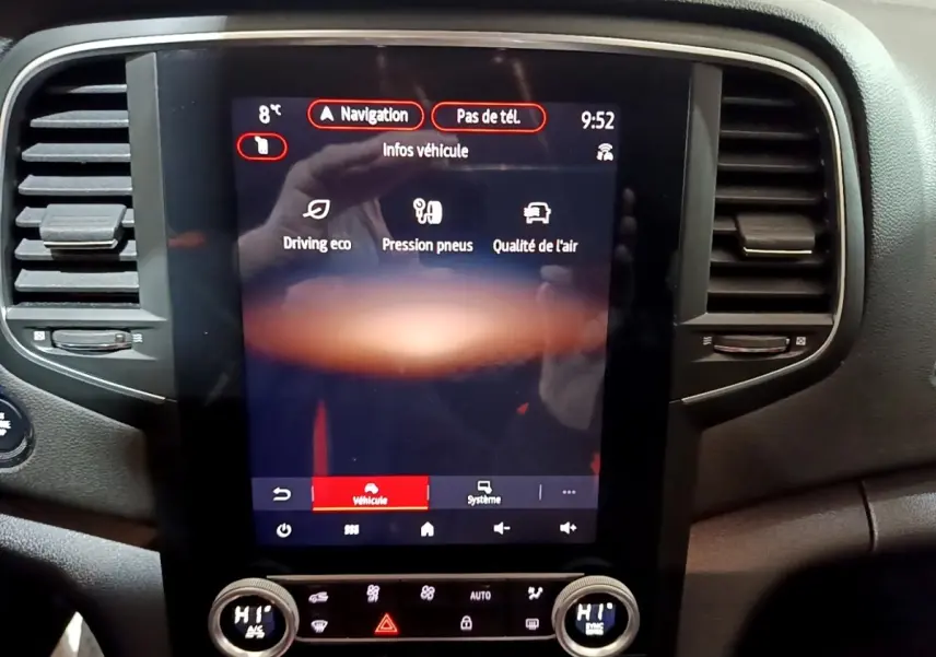 Vue rapprochée du tableau de bord central tactile noir de la Renault Mégane blanche 2023, affichant les infos véhicule.