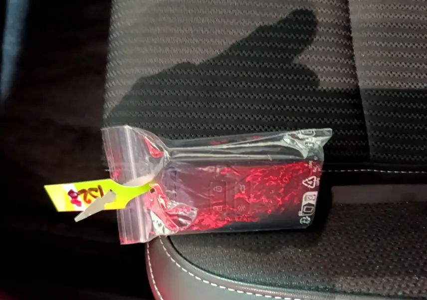 Télécommande Renault Megane Techno TCe 140 EDC 2023 emballée, posée sur siège tissu noir avec surpiqûres blanches.