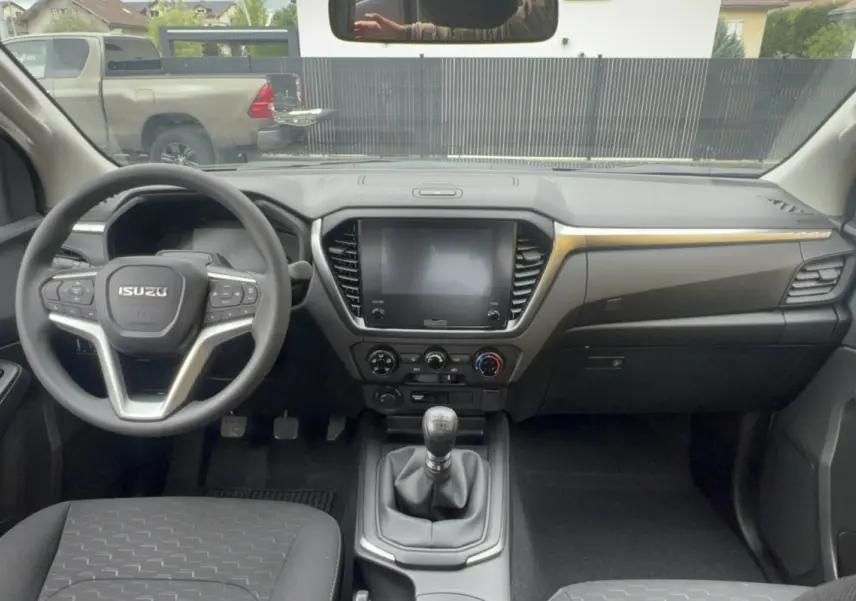 Vue intérieure avant de l'Isuzu D-MAX 2026 avec tableau de bord noir et volant multifonctions.
