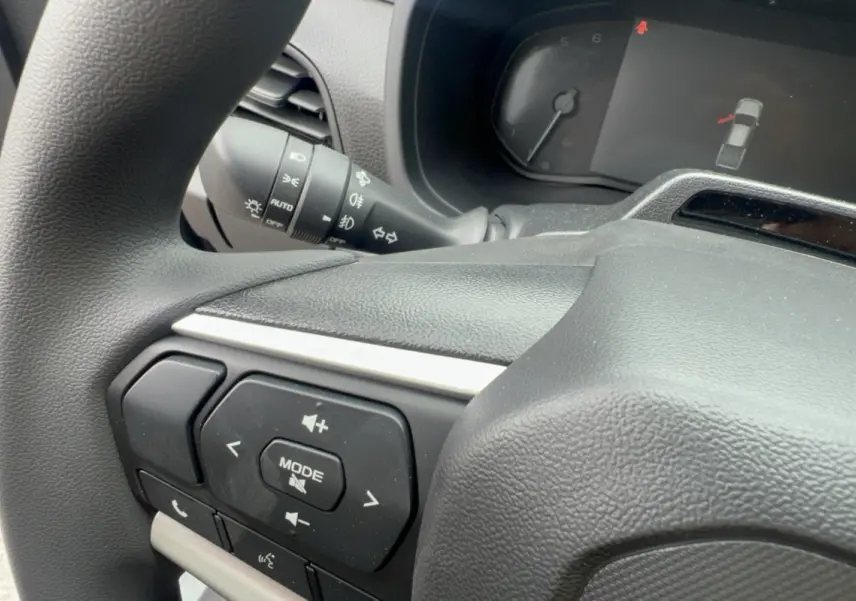 Gros plan sur le volant multifonctions noir de l'Isuzu D-MAX 2.2 TD 164 Space Evolution, avec commandes audio visibles.