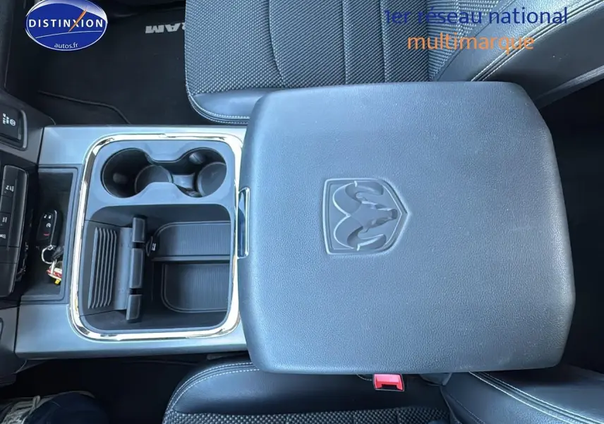 Vue plongeante sur la console centrale noire du Dodge RAM 5.7 V8 Crew Sport 2020 avec porte-gobelets et logo RAM embossé.