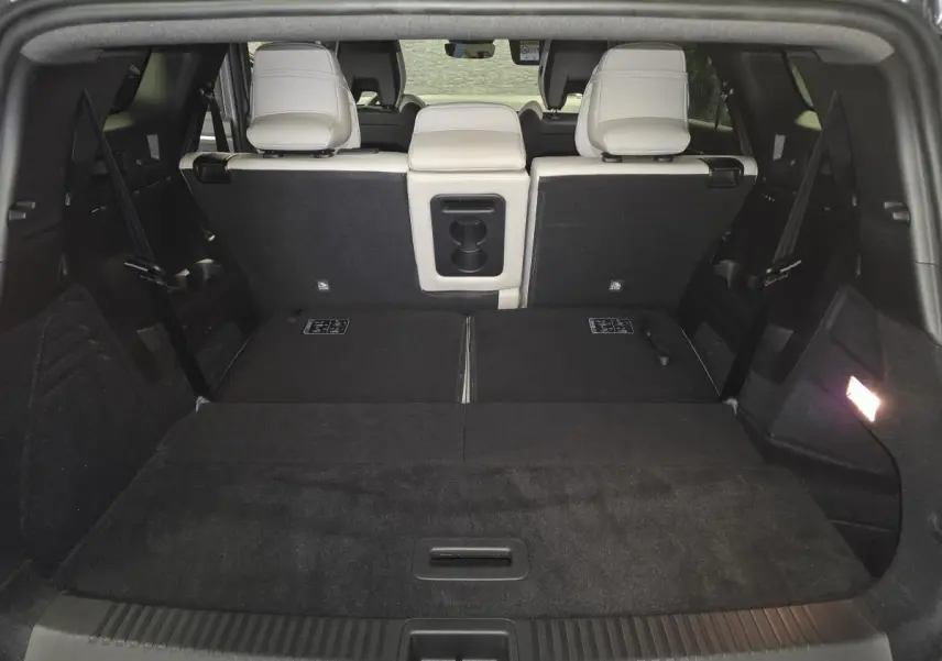 Coffre ouvert vu de l'arrière du Renault Espace gris, avec banquette arrière partiellement rabattue et sellerie claire.