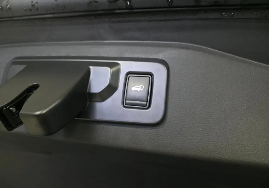 Bouton d'ouverture électrique du hayon sur panneau intérieur noir du Renault Espace gris 2025 hybride