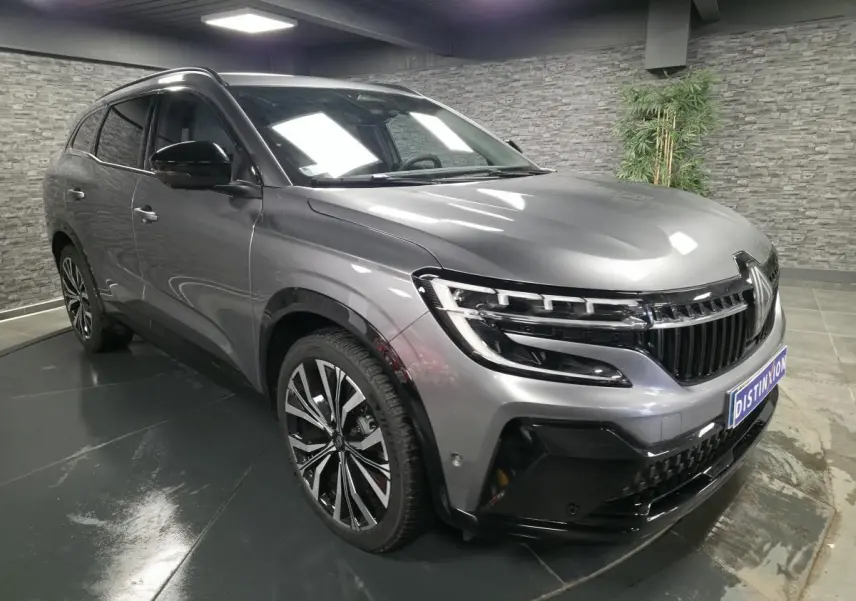 Renault Espace 2025 gris Baltique en 3/4 avant droit, avec calandre noire brillante et jantes alliage 20 pouces.