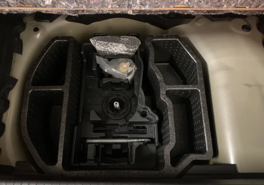 Rangement en mousse noir dans le coffre d'une Peugeot 208 gris, vue plongeante sur les compartiments vides.