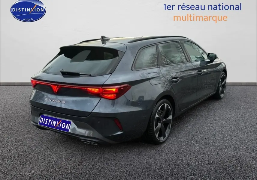 Vue 3/4 arrière droite d'une CUPRA Leon ST gris magnétique avec feux arrière LED allumés sur fond neutre.