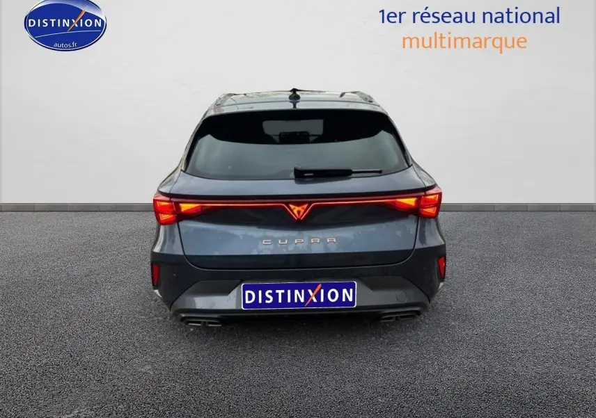 Vue arrière d'une CUPRA Leon ST gris magnétique avec feux LED allumés et double sortie d'échappement visible.