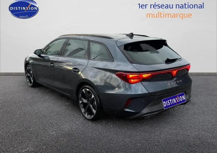 Vue 3/4 arrière droite d'une CUPRA LEON ST 2025 gris magnétique avec feux arrière LED allumés et jantes alu noires.