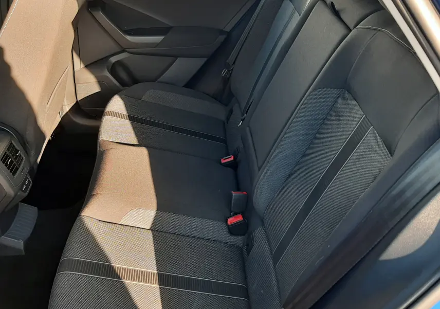 Vue intérieure côté droit des sièges arrière en tissu gris du Volkswagen T-Roc bleu 2022, avec ceinture et porte ouvert.