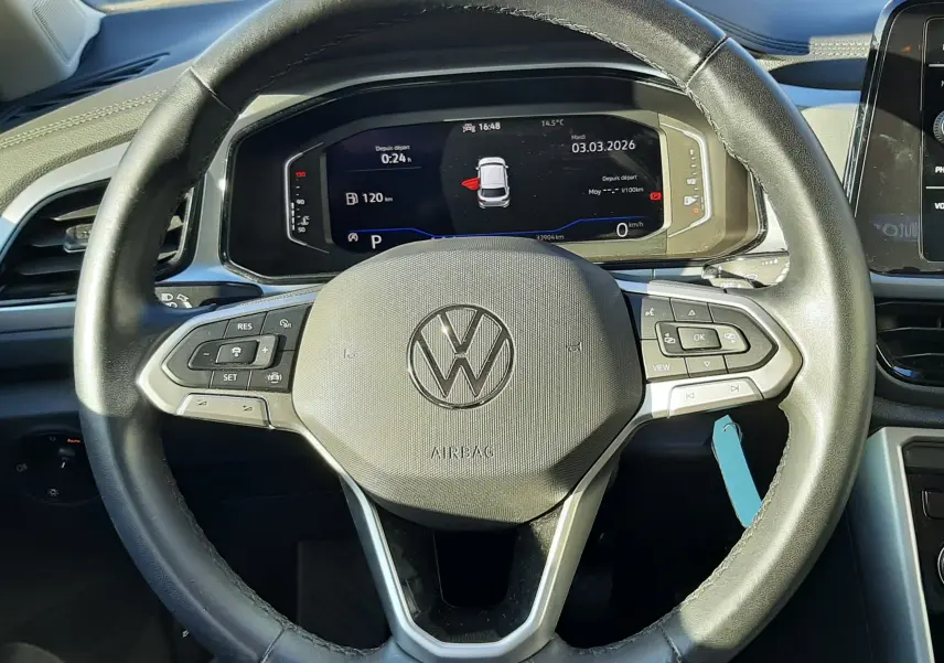 Vue centrée sur le volant noir du Volkswagen T-Roc 2022 avec tableau de bord digital allumé en arrière-plan.