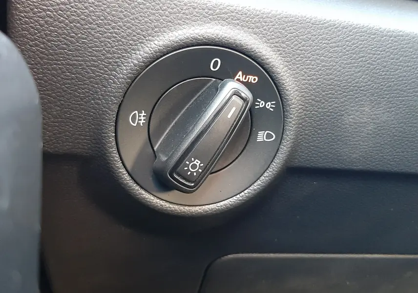 Gros plan sur le sélecteur de phares du Volkswagen T-Roc 1.5 TSI 150CH LIFE DSG7, intérieur noir texturé.