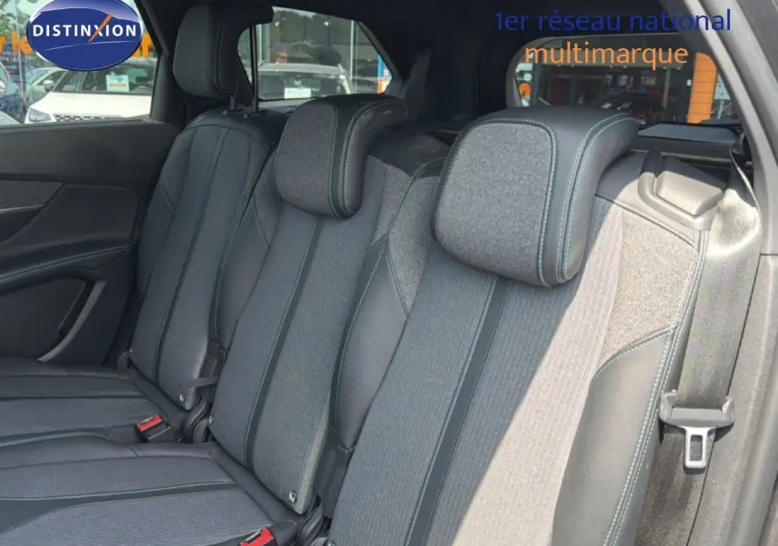 Vue intérieure sur les sièges arrière du Peugeot 5008 2023, tissu gris avec surpiqûres bleues et ceintures visibles.