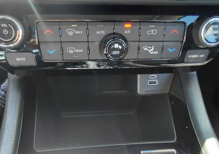 Vue rapprochée du tableau de bord et de la console centrale noire du Jeep Compass 2025, avec commandes climatisation et ports USB visibles.