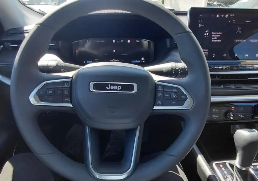 Vue intérieure centrée sur le volant Jeep et le tableau de bord avec écran tactile et levier de vitesse.