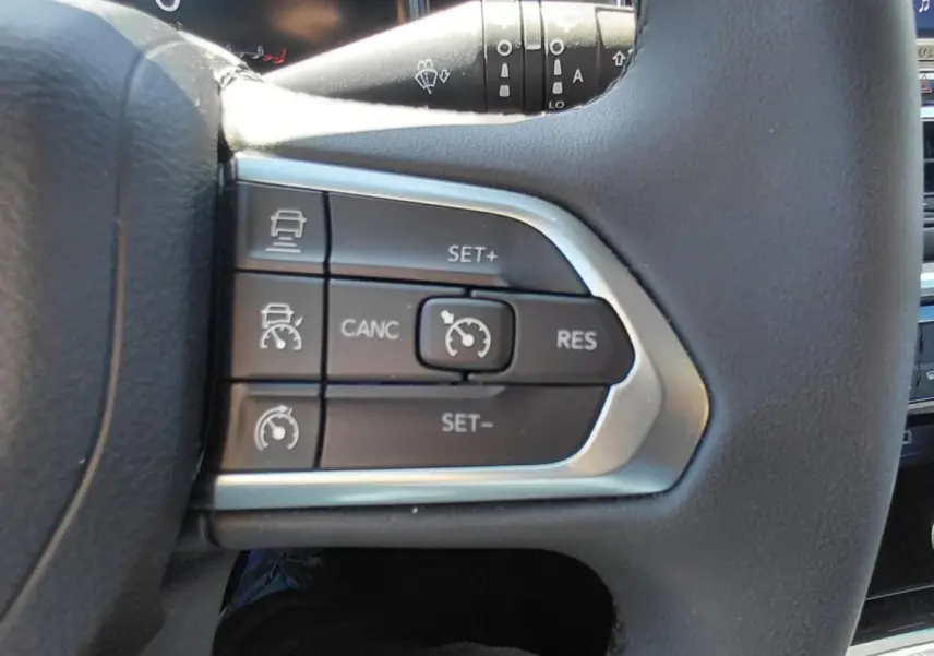 Gros plan sur les commandes du régulateur de vitesse au volant du Jeep Compass bleu 2025.