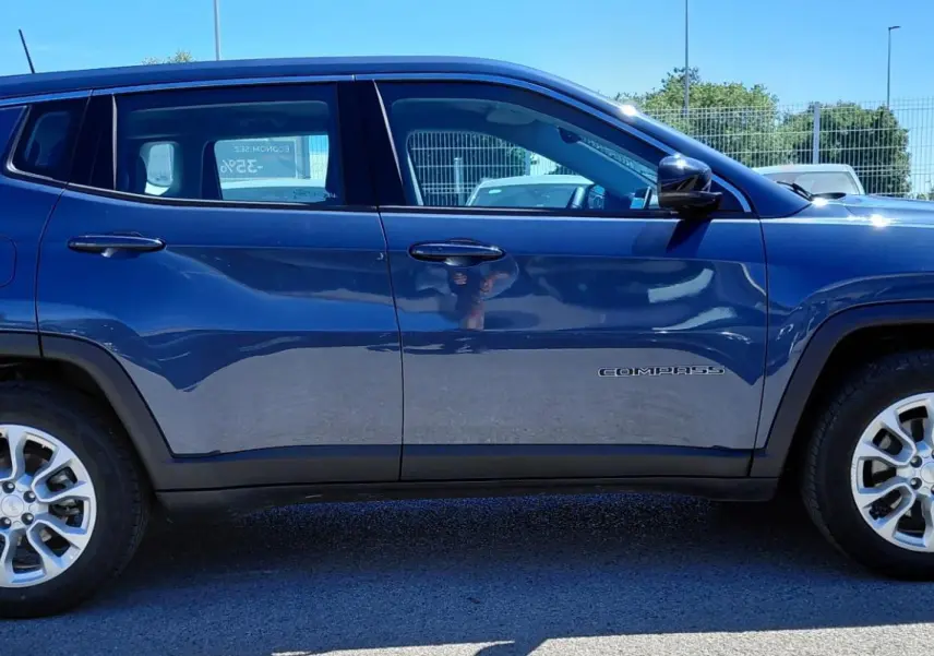 Vue latérale droite d'un Jeep Compass bleu 2025 avec jantes alliage 18 pouces et logo Compass sur la porte.