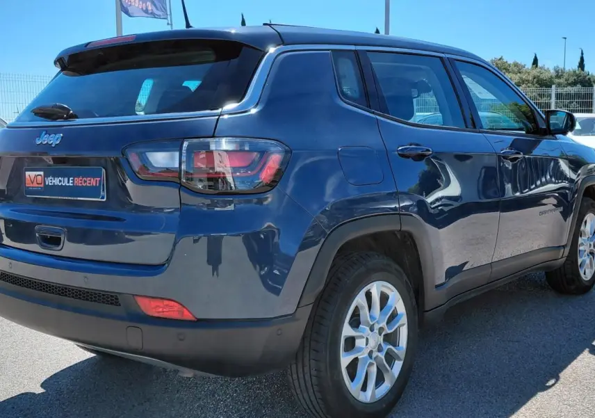 Vue 3/4 arrière droite d’un Jeep Compass bleu 2025 avec jantes alliage 18 pouces et feux arrière LED.
