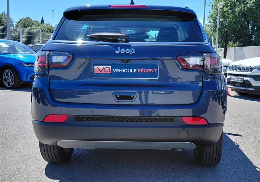 Vue arrière d’un Jeep Compass bleu 2025 avec feux LED et plaque « Véhicule récent » visible en extérieur.
