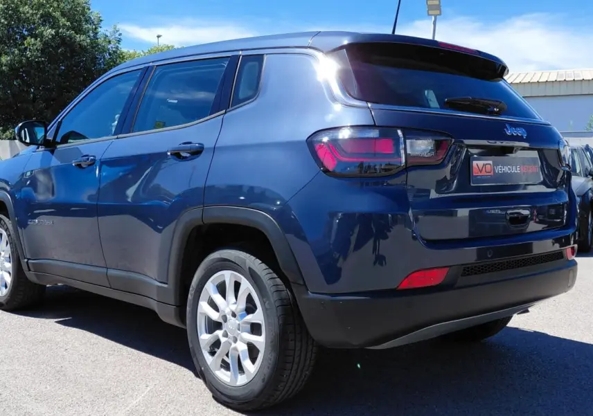 Jeep Compass bleu vue 3/4 arrière droit, jantes alliage 18 pouces et feux arrière LED visibles.