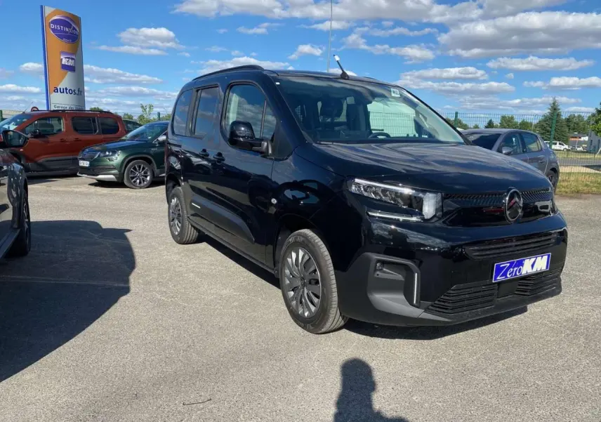 Citroën Berlingo noir vu en 3/4 avant droit sur parking, avec calandre moderne et phares LED visibles.