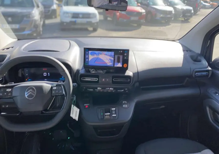 Vue intérieure avant du tableau de bord noir du Citroën Berlingo 2026 avec écran central affichant la caméra de recul.