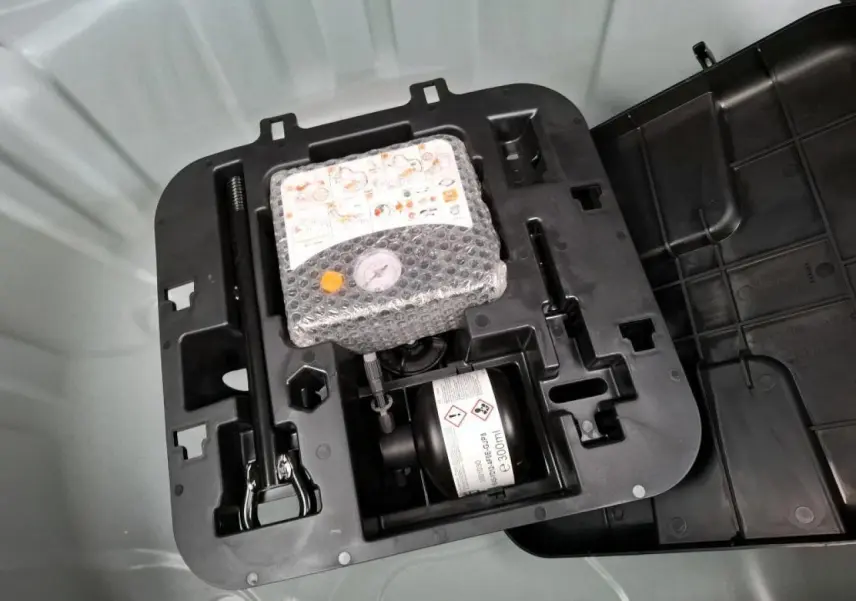 Détail du kit de gonflage pneumatiques dans le coffre d'une Renault Clio blanche 2024, version Tce 90 cv.