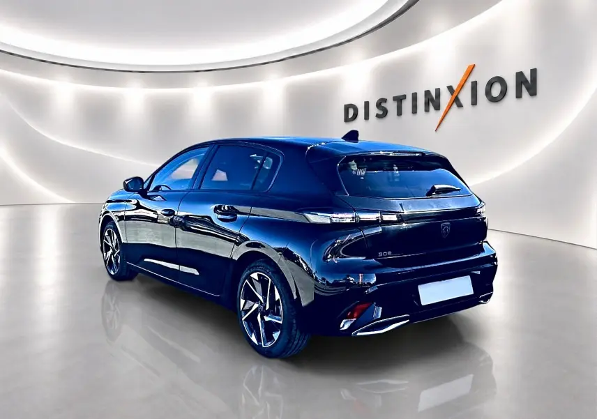 Peugeot 308 noire vue 3/4 arrière droit en intérieur, avec jantes alu et feux arrière LED distinctifs.