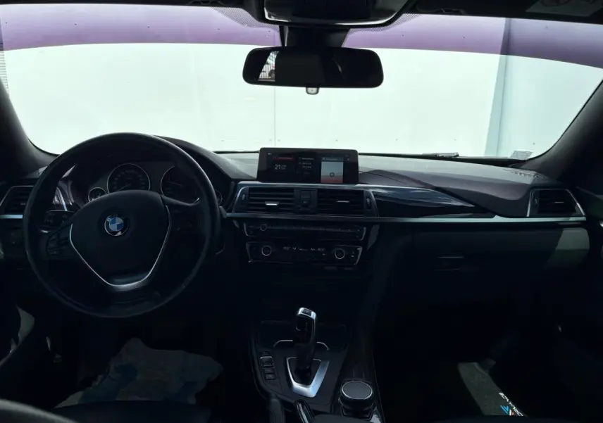 Vue intérieure avant du tableau de bord et volant cuir de la BMW Série 4 Gran Coupé noir avec écran central et levier de boîte automatique.