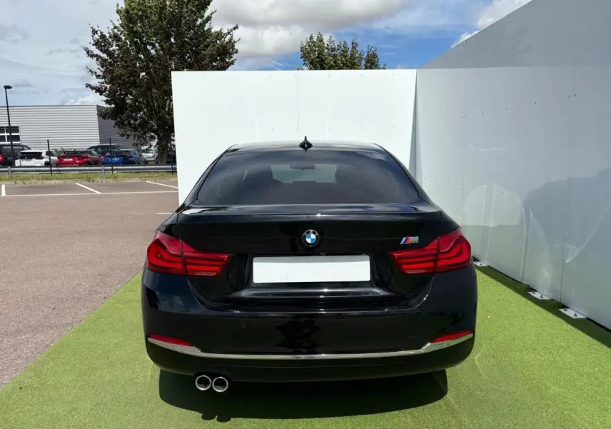 Vue arrière d'une BMW Série 4 Gran Coupé noire avec double sortie d'échappement et logo M sur le coffre.