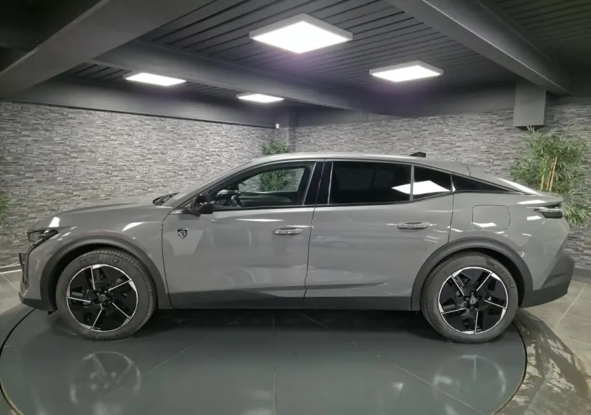 Profil droit de la Peugeot 408 gris Selenium 2024 hybride rechargeable avec jantes alliage 19 pouces et vitres teintées.