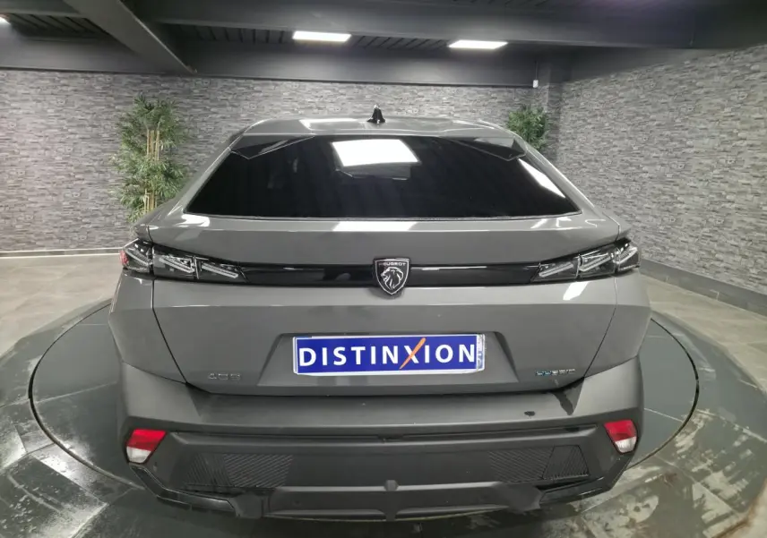 Vue arrière d'une Peugeot 408 gris Selenium hybride rechargeable avec feux arrière à effet griffe et logo noir brillant.