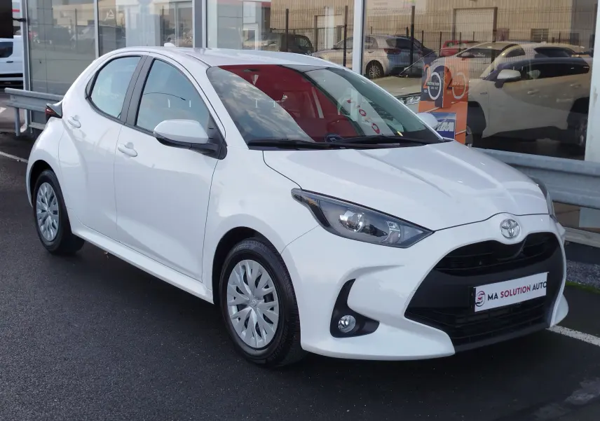 Toyota Yaris blanc pur vue 3/4 avant droit, avec calandre noire et jantes acier à enjoliveurs.