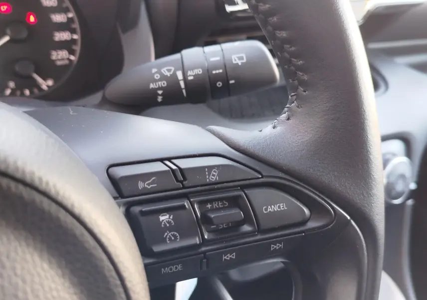 Détail du volant côté droit de la Toyota Yaris blanche 2023, avec commandes de régulateur et assistant de conduite.