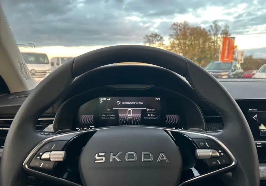 Vue intérieure centrée sur le volant cuir noir du Skoda Kamiq 2025 avec tableau de bord digital allumé.