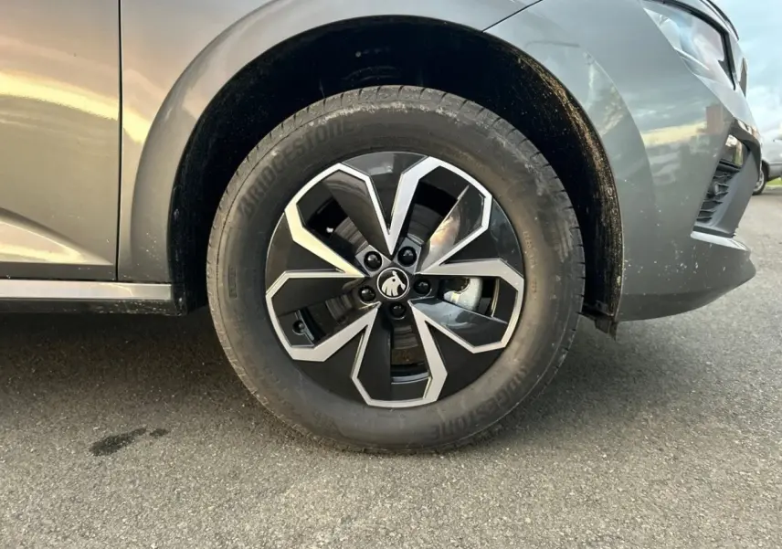 Gros plan sur la roue avant gauche gris clair d'un Skoda Kamiq 2025 avec jante alliage au design géométrique noir et argent.