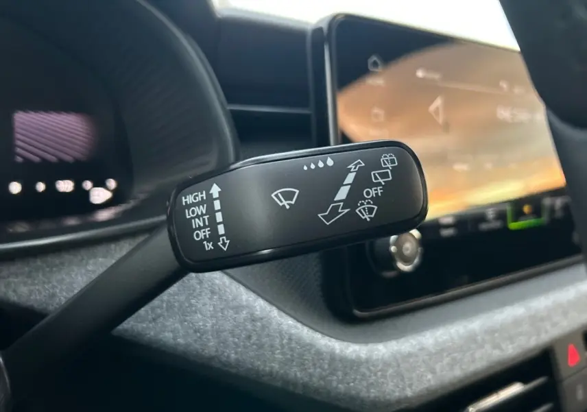 Gros plan sur la commande d'essuie-glace à gauche du volant dans l'habitacle gris clair du Skoda Kamiq 2025.