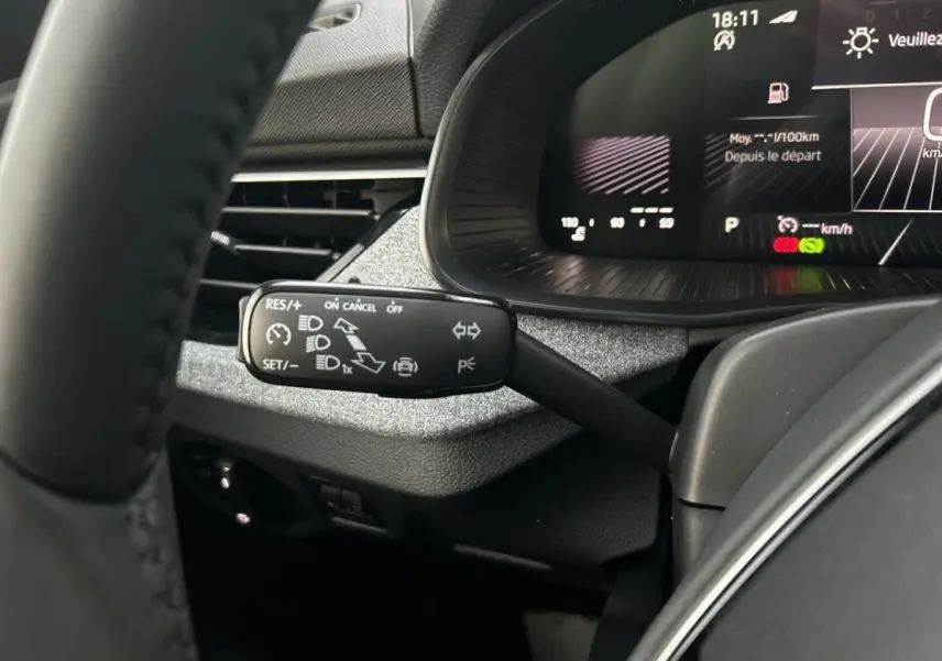 Gros plan sur la manette de régulateur de vitesse à gauche du volant du Skoda Kamiq gris clair, avec tableau de bord numérique en arrière-plan.