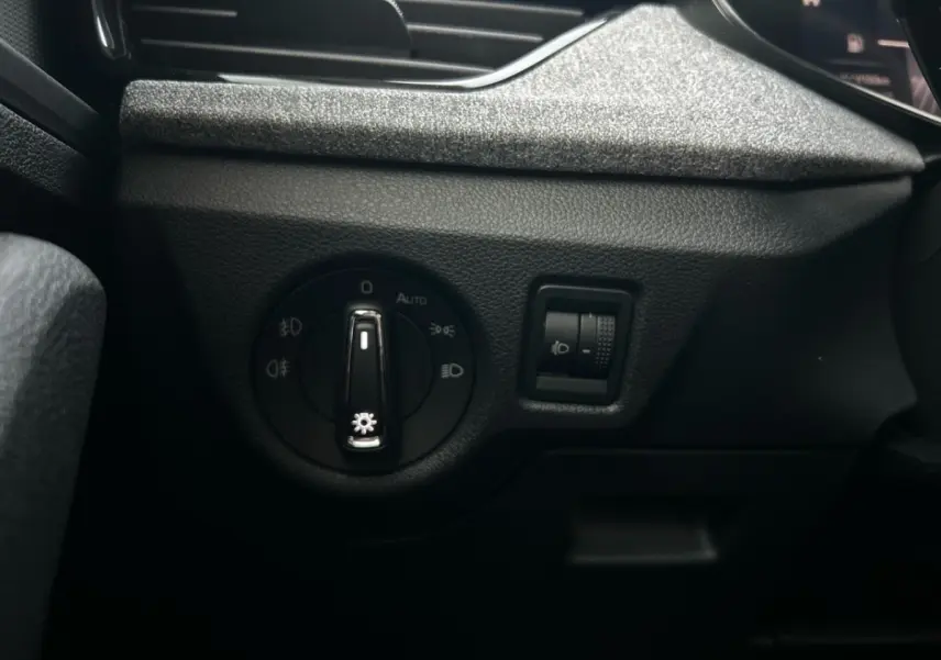 Gros plan sur les commandes d'éclairage côté gauche du tableau de bord noir du Skoda Kamiq gris clair 2025