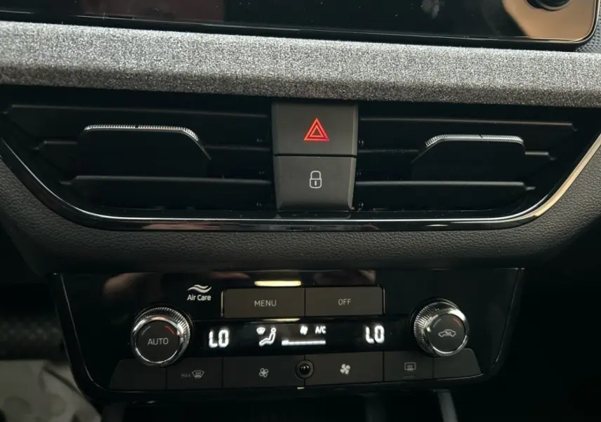 Détail du tableau de bord central noir du Skoda Kamiq 2025 montrant la commande de climatisation automatique bi-zone et les boutons d'alerte.