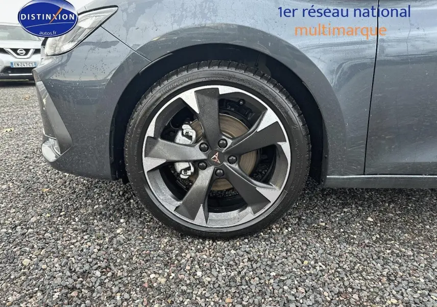 Gros plan sur la roue avant gauche et la jante alu grise du CUPRA LEON ST gris magnétique, avec partie avant du véhicule visible.