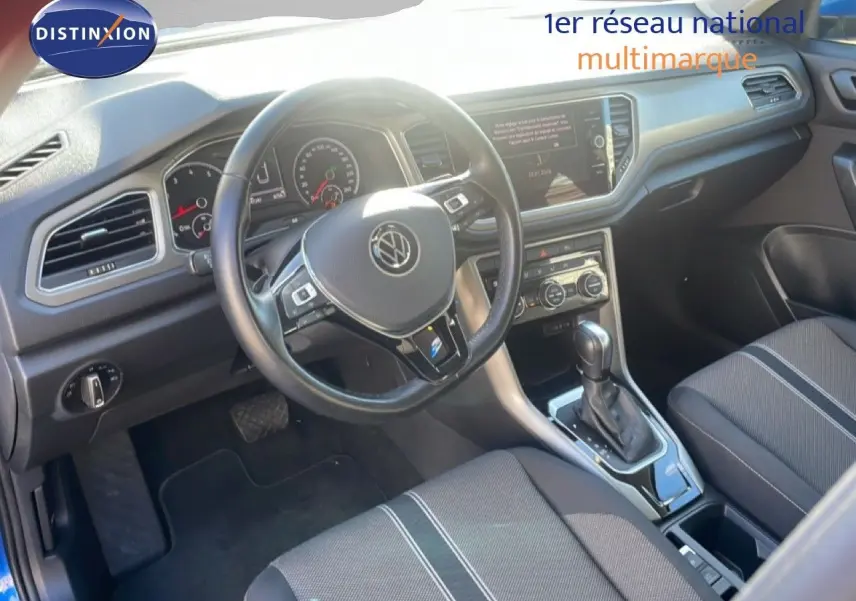 Vue intérieure du Volkswagen T-Roc 1.5 TSI 2021, montrant le volant, la console centrale et les sièges en tissu noir.