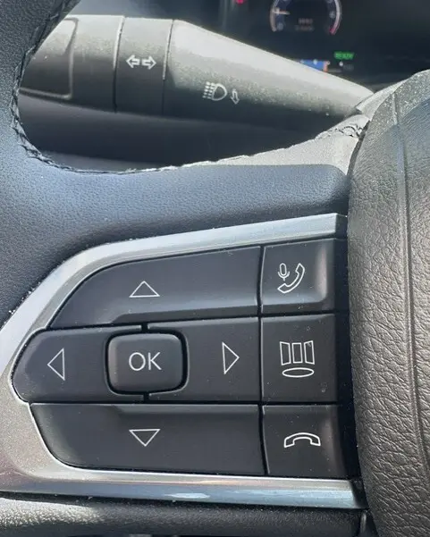 Gros plan sur les commandes multifonctions au volant du Jeep Compass noir 2025, avec boutons de navigation et téléphone.