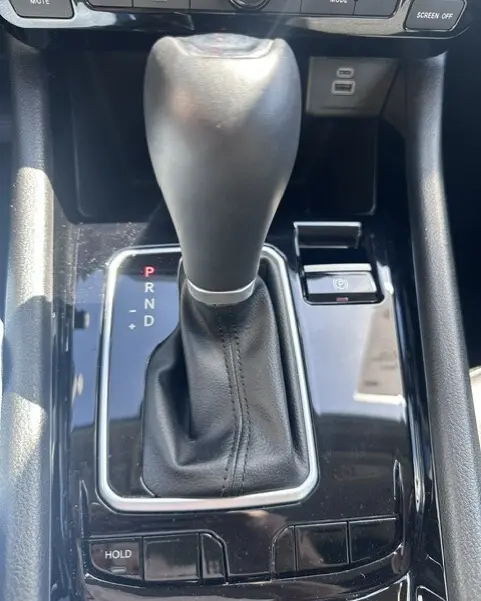 Gros plan sur le levier de vitesses automatique noir du Jeep Compass 2025 avec bouton frein à main électronique et commandes autour.