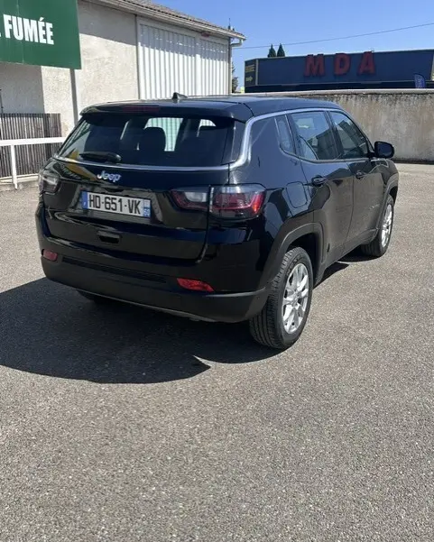 Vue 3/4 arrière droite du Jeep Compass noir 2025 avec jantes alliage 18 pouces, sur parking extérieur ensoleillé.