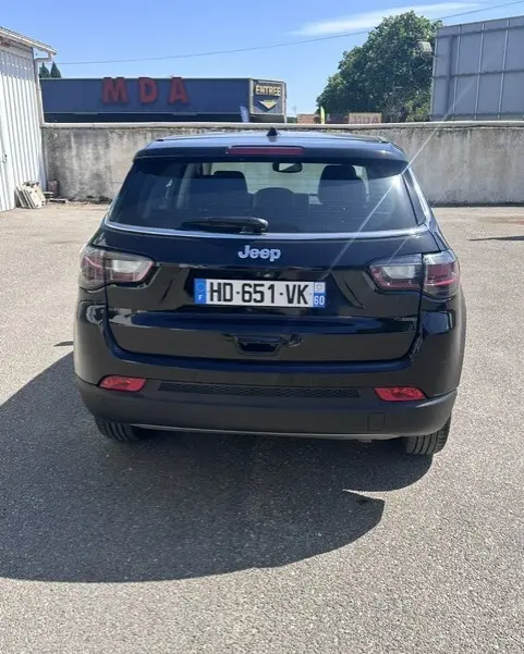 Vue arrière d'un Jeep Compass noir 2025 garé, mettant en valeur ses feux LED et sa silhouette compacte.