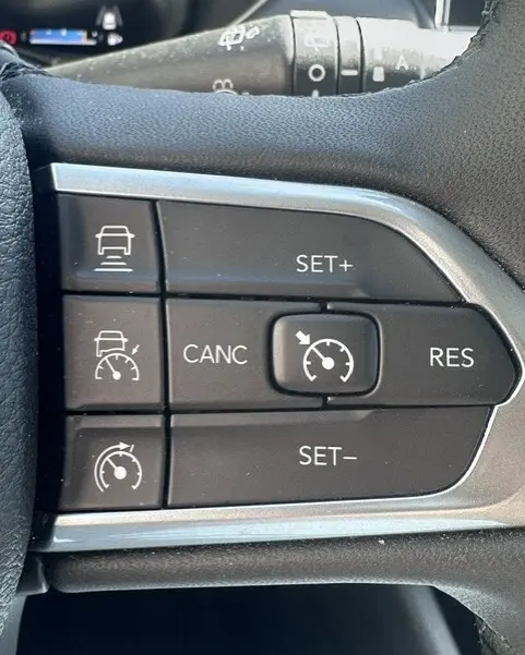 Gros plan sur les commandes du régulateur de vitesse au volant du Jeep Compass noir 2025, version e-Hybrid Altitude.